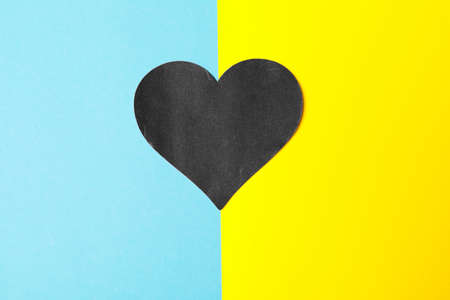 There is no war. blue and yellow heart made of paper in female hands on a blue background. conceptual war in Ukraineの写真素材