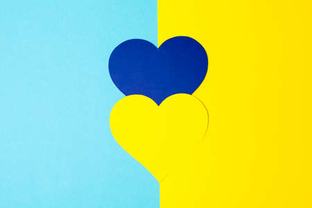 There is no war. blue and yellow heart made of paper in female hands on a blue background. conceptual war in Ukraineの写真素材