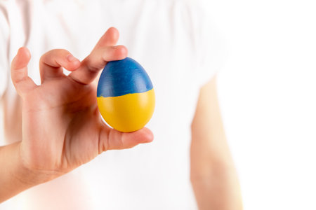 Little girl holding easter eggs on blue and yellow background. easter eggs in Ukraine flag.の写真素材