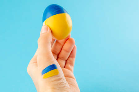 Easter egg in woman hand on Ukraine flag colors as concept for war Ukraine.の写真素材