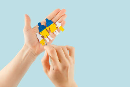 Woman hands hold a paper-cut family painted in the national colors of Ukraine. Ukrainian flag