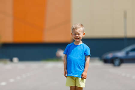 a boy in a blue and yellow t-shirt on the background of the street. national flag of ukraine. Mockup for printの写真素材