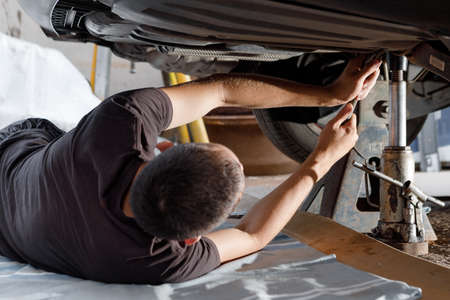 An auto mechanic works in a garage. Car repair