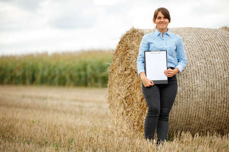 Beautiful girl agronomist with note book and analyzes the corn crop.