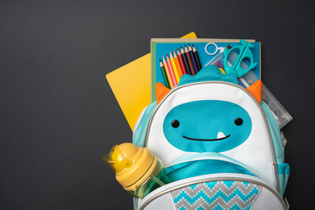 Backpack with school supplies on a blue and yellow background. View from above. copy space. Back to...