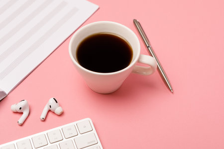 Notebook for writing notes and a cup of coffee on a pink background, flat lay. music notebook