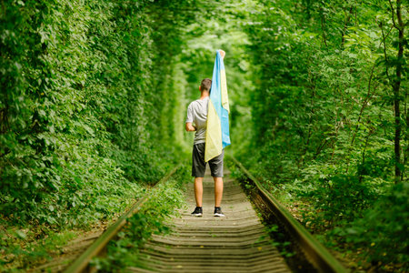 man raised his hands and holds the Ukrainian flag behind his back. concept Ukrainian patriot, rally in support of Ukraineの写真素材