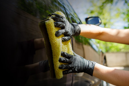 woman polishes the car, uses a microfiber cloth and polish to wipe the cars body with polish.の写真素材