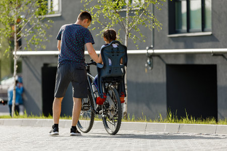 father riding bike with son in bike seat.の写真素材