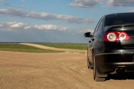 car on a dirt road in a field of sunflowers and wheat with sunlight.