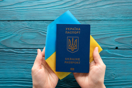 international passport of ukraine in female hands against the background of the national flag. war on ukraineの写真素材
