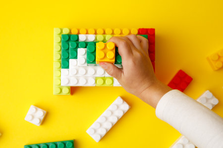 hand stacking up the colorful plastic block. the child is playing with the constructorの写真素材
