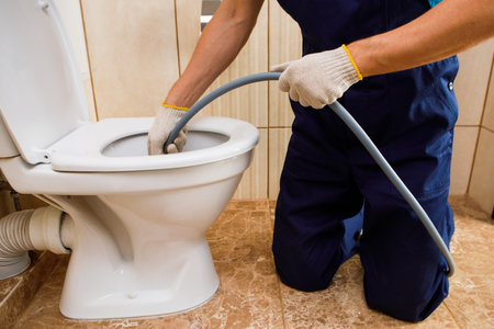 plumber unclogging blocked toilet with hydro jetting at home bathroom. sewer cleaning serviceの写真素材