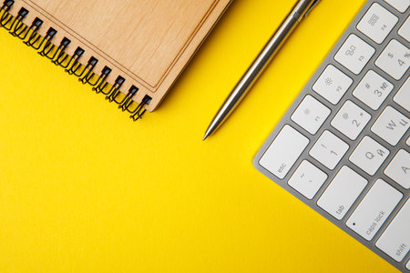 Office desk workspace on bright color yellow background. notepad on yellow backgroundの写真素材