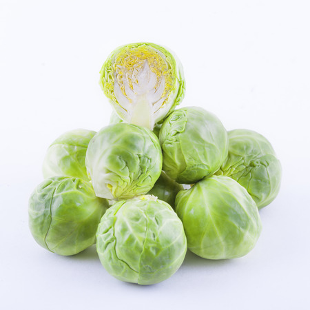 Low angle shot of brussels sprouts stacked on top of each other with one sprout halfed. Isolated on whiteの写真素材