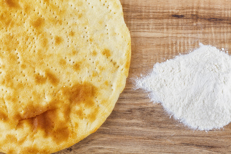 Overhead shot of baked pastry and flour on a wooden tableの写真素材