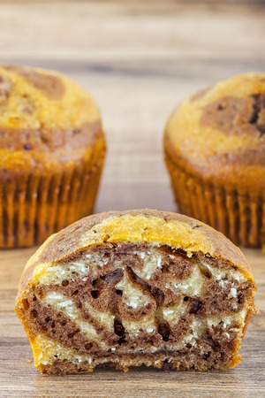 Close-up shot of a half eaten muffin with a small group of muffins behind.の写真素材