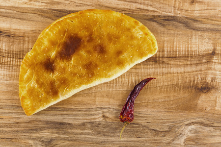 Overhead shot of a panzerotti and a red hot pepper on a table.の写真素材
