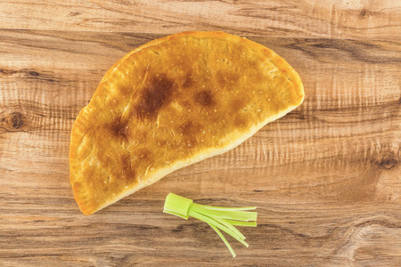 Overhead shot of baked pastry panzerotti and leek on a wooden table.の写真素材