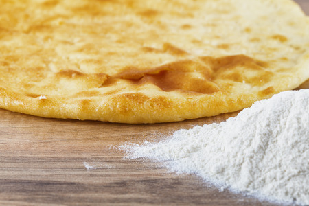 Low angle shot of baked pastry and flour on a wooden tableの写真素材
