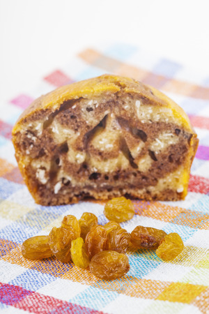 Close up low angle shot of a half eaten muffin and a large group of raisins on a cloth rag with a white background.の写真素材