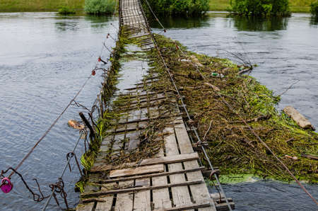 Suspension bridge over the river is broken and flooded. The consequences of flooding after a dam...