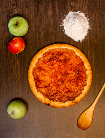 Sweet apple pie on a table with apples and flourの写真素材