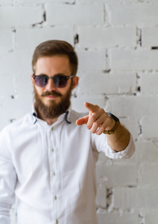 Young man with beard and mustache in sunglasses in front of white brick wallの写真素材