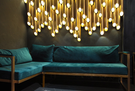 Modern lounge bar interior.Dark tone.Dark cyan sofa .Golden laterns in form of tubes.の写真素材