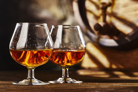 Two glass of Cognac and old oak barrel defocussedの写真素材