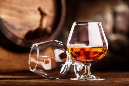 Two glass of Cognac and old oak barrel defocussedの写真素材