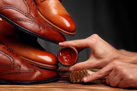 Four toes one on one of brown shoes brogues and derby on the wooden table.Brush and cream.Shoes shine. concept shoe careの写真素材