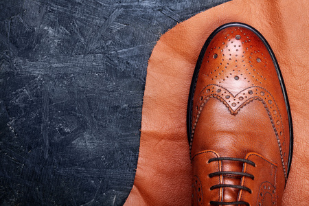 Fashion classical polished men's brown oxford brogues on piece of leather dark wooden background.Top view.Copy spaceの写真素材