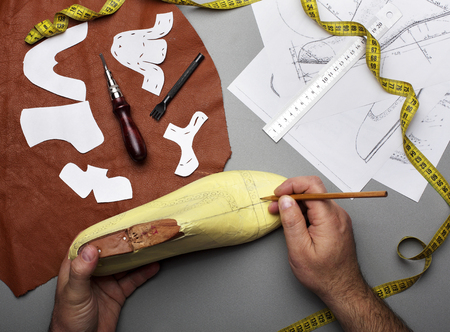 Modelling design of a shoes.Workplace of shoe designer.Hands of designer draw a shoe design .Copy spaceの写真素材