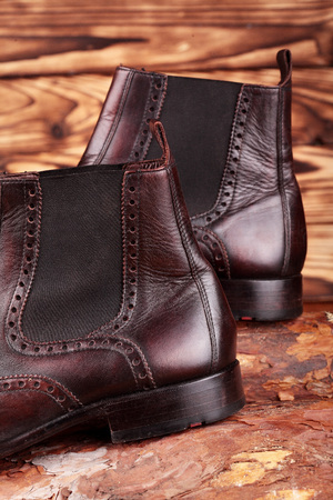 Brown leather chelsea boots polished on pine board. Waxing boots.Copy space.Closeupの写真素材