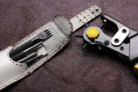 Leather craft tools on a bordo leather backgroundの写真素材