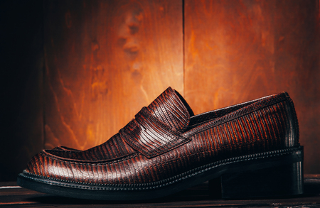 Mocasine shoes of snake skin on fire red wooden background.の写真素材