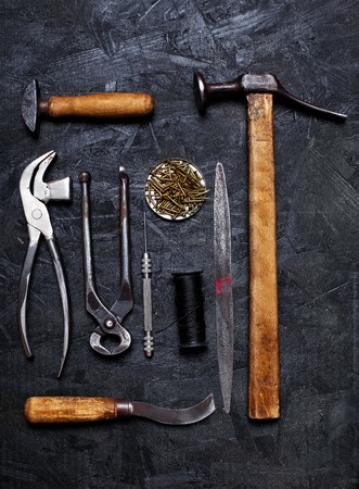 Set of cobbler vintage tools pliers nippers hook sewing cobbler's hammer on the dark wooden background. Top viewの写真素材