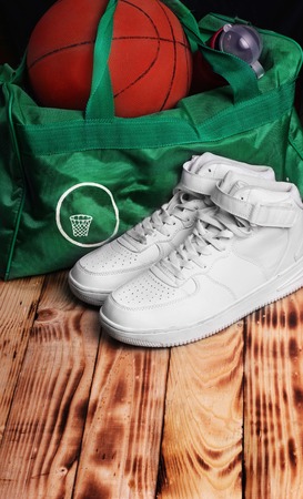 Pair of high white sneakers , Sport bag for basketball, Basketball ball inside the bag, sport bottle with water.Wooden background.Background.Concept basketball training.Top view. free space.の写真素材