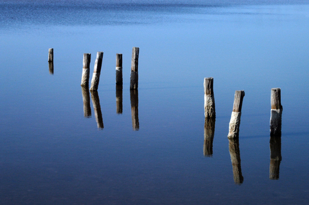 The remnant pilings of a long-gone dock appear to float in air due to their reflection in the blue, still water of a pond near NASA Kennedy Space Center. This image furnished by NASAのeditorial素材