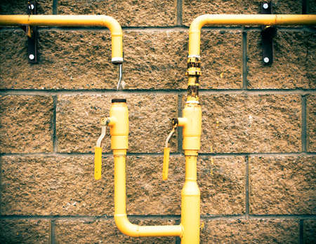Yellow gas pipe on a stone. brick wall. The gas pipe does not hold gas.の写真素材
