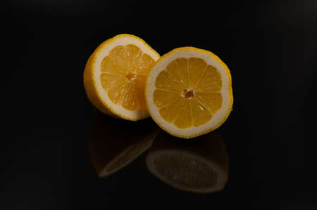 Close-up of a lemon cut in half with reflection on an isolated black background.の写真素材