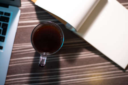Close-up of a wood work desk with coffee cup, laptop and notes, top view.の写真素材