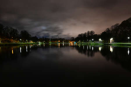 Promenade at night, in the middle of which the pond reflects the lights of lanterns.
