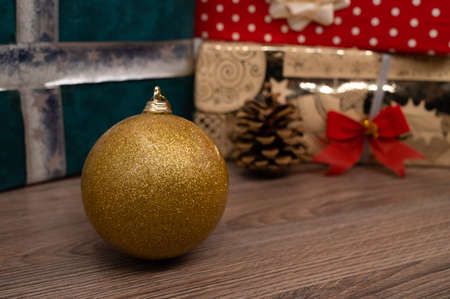 Close-up of a christmas bulb with gift boxes in background.の写真素材