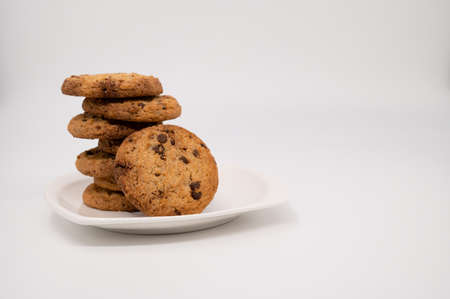 Close-up of a gingerbread cookie with chocolate leans on a stack on a white plate isolated on a...