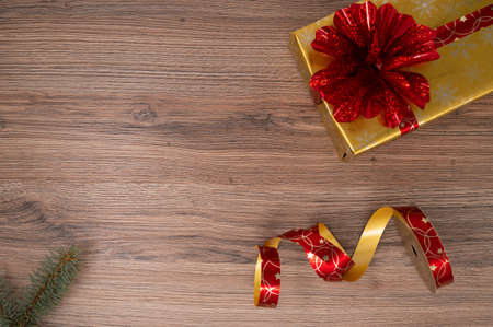 Gold gift box with red bouquet with red christmas bulbs and wrapping tape on a wooden table. Top view.の写真素材