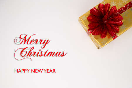 Close up of a gold Christmas gift box with red bouquet and wrapping tape on an isolated white...