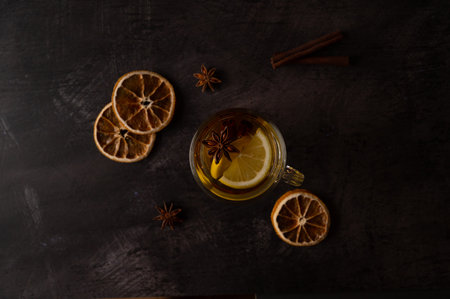 Black tea with lemon slices, star anise and cinnamon in a glass teacup on a black metallic background. Top view.の写真素材