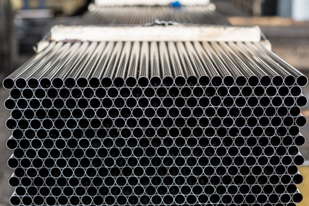 Industrial background. Close up of internal metal pipes in a warehouse. Stack of new and shiny steel...